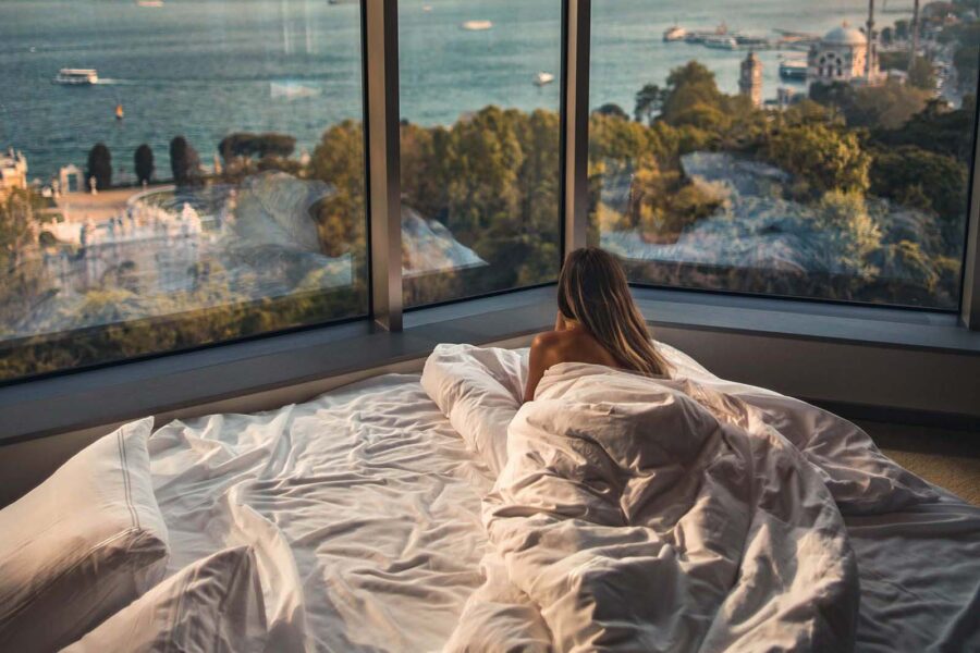 Woman in hotel bed looking out the window