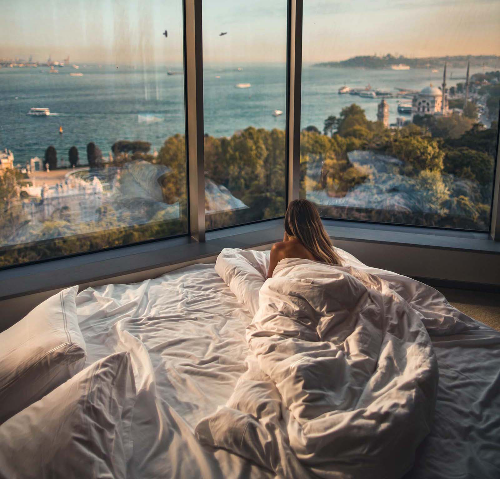 Woman in hotel bed looking out the window